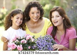 Senior Woman With Adult Daughter And Granddaughter Gardening Together