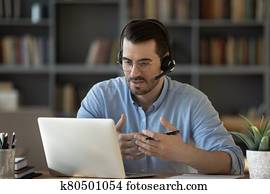Confident man teacher wearing headset speaking, holding online lesson Confident man teacher wearing headset speaking, holding online lesson