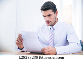 Businessman sitting at the table reading document Businessman sitting at the table reading document