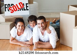 Happy family lying on the floor after buying house with boxes