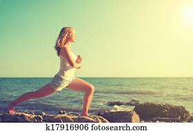 young woman doing yoga on  beach