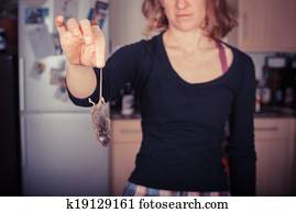 Woman holding a dead mouse in her kitchen