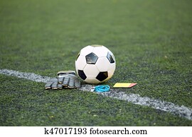 ball, gloves, whistle and cards on soccer field ball, gloves, whistle and cards on soccer field