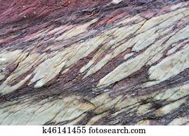 Close up of colorful rock surface, natural background, pattern and texture. Metamorphic white quartzite folded and fractured together with red coarse sandstone, due to the power of geologic crustal movement.