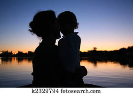 the silhouette of mother with the child against the background of the sunset the silhouette of mother with the child against the background of the sunset