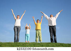 family of four on grass with hands up