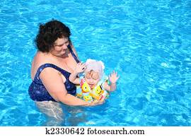 The grandmother plays with the granddaughter in pool