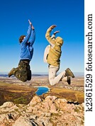 Two hikers jumping cheerfully on mountain summit