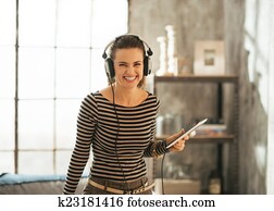 Portrait of smiling young woman listening music in headphones in