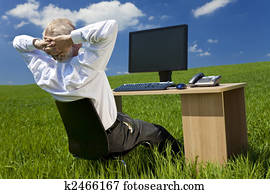 Businessman Relaxing at Desk With Computer In A Green Field