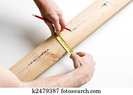 Detail of man marking piece of timber using pencil and tape measure