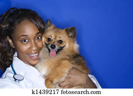 Woman veterinarian holding brown dog.