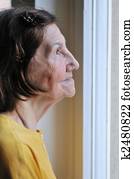 Solitude - senior woman looking through window