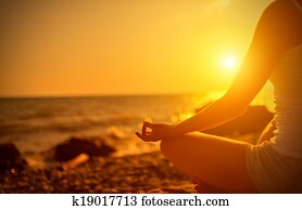 hand of  woman meditating in a yoga pose on beach at sunset