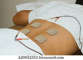 Patient applying electrical stimulation therapy ( TENS ) on his back Patient applying electrical stimulation therapy ( TENS ) on his back