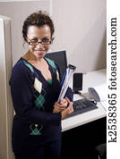Hispanic businesswoman standing next to cubicle desk