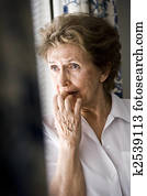 Sad elderly woman looking out window