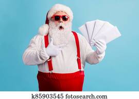 Portrait of his he nice attractive amazed stunned thick white-haired Santa holding in hand demonstrating mail gifts wish list omg isolated bright vivid shine vibrant blue color background Portrait of his he nice attractive amazed stunned thick white-haired Santa holding in hand demonstrating mail gifts wish list omg isolated bright vivid shine vibrant blue color background