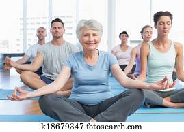 Sporty people in lotus pose at fitness studio