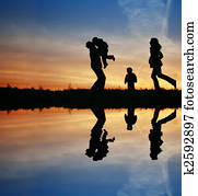 silhouette family of four and water