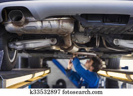 Exhaust of a car with mechanic underneath Exhaust of a car with mechanic underneath
