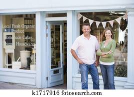 Couple standing in front of organic food store smiling Couple standing in front of organic food store smiling