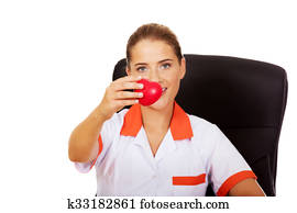 Female doctor sitting behind the desk and holding heart toy