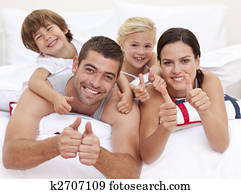 familia, acostado, en, padre, cama, con, pulgares arriba