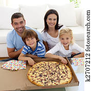 Family eating pizza on sofa