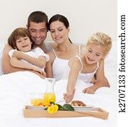 Happy family having breakfast in bedroom