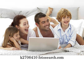 Happy family in bed using a laptop