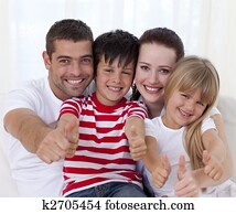 Portrait of smiling family sitting on sofa together with thumbs up