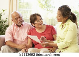 Senior Couple Talking To Financial Advisor At Home
