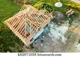 Aerial view of unfinished brick house with wooden roof structure under construction. Aerial view of unfinished brick house with wooden roof structure under construction.
