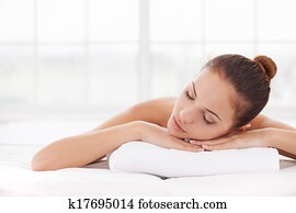 Spa woman. Beautiful young woman keeping eyes closed while lying on massage table
