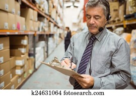 Warehouse manager writing on clipboard Warehouse manager writing on clipboard