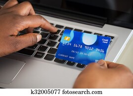 Person's Hand Using Debit Card While Shopping Online