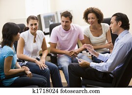 Man giving lecture to four people in computer room Man giving lecture to four people in computer room