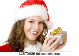Young women in Santa Claus dress is holding a Christmas present on her ear, to find out what is inside. Isolated on white.