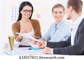 Creatively charged! Group of three designers gathered around a table discussing a sketch