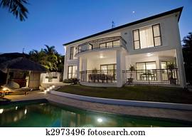 Luxurious mansion exterior at dusk overlooking pool