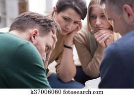 People comforting young man during group therapy session