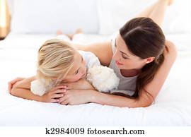 Jolly mother talking with her little girl 