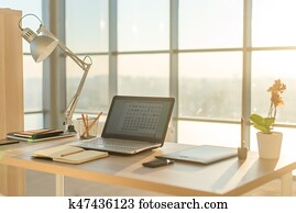 Side view picture of studio workplace with blank notebook, laptop. Comfortable work table, home office.