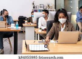 African office worker with asian team in new normal social distance office