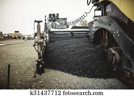 Paver machinery laying fresh asphalt or bitumen during road construction on building site. vintage, retro effect on photo