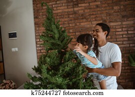 asian father with daughter set up christmas tree together asian father with daughter set up christmas tree together