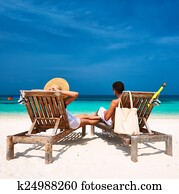 Couple in white relax on a beach at Maldives
