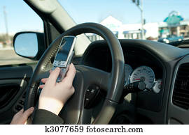 Hand of a teen texting while driving