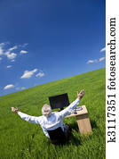 Businessman Celebrating Arms Raised At Desk In Green Field